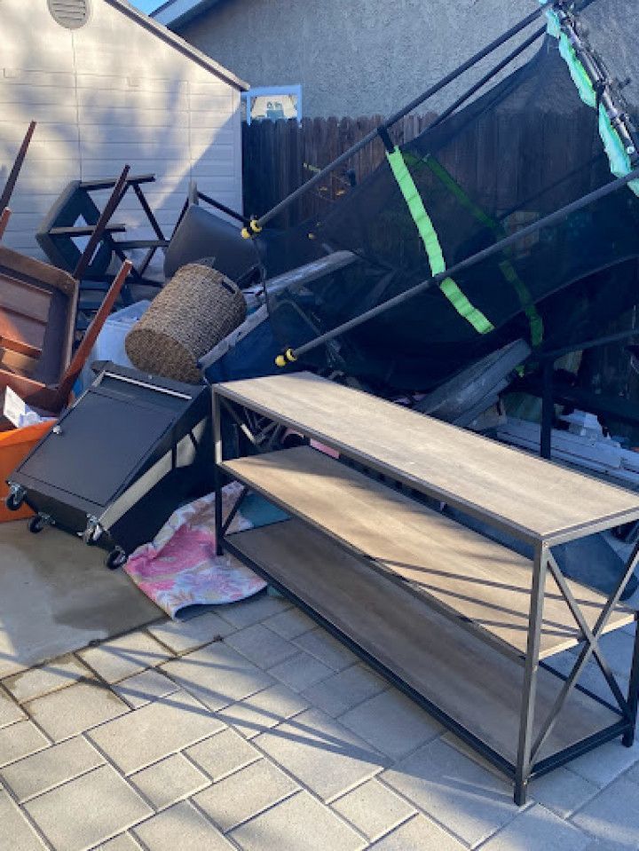 A pile of furniture is sitting on a patio in front of a house.