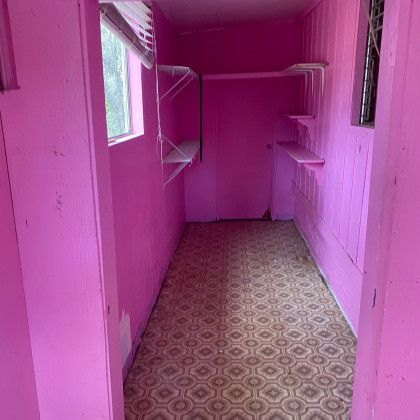 A long pink room with shelves and a window.