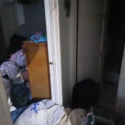 A room with a lot of clothes on the floor and a dresser.