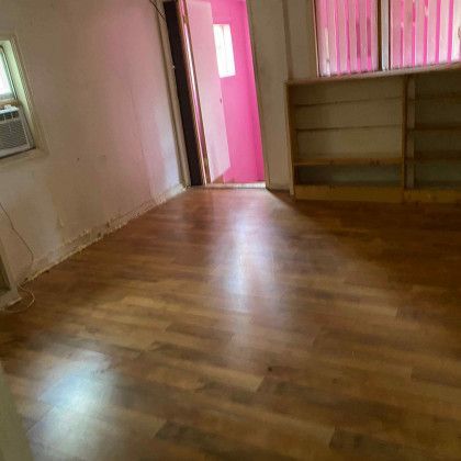 An empty room with hardwood floors and a pink door.