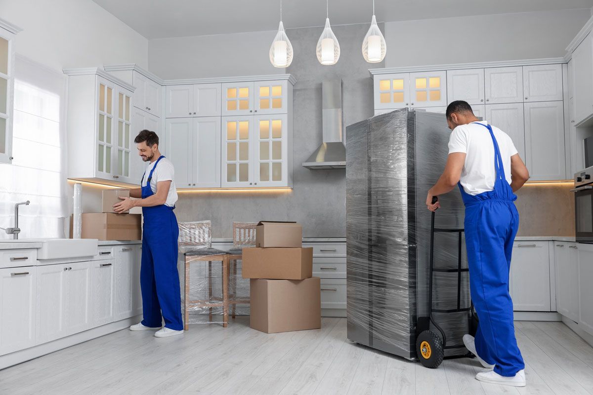 Two men are moving a refrigerator in a kitchen.