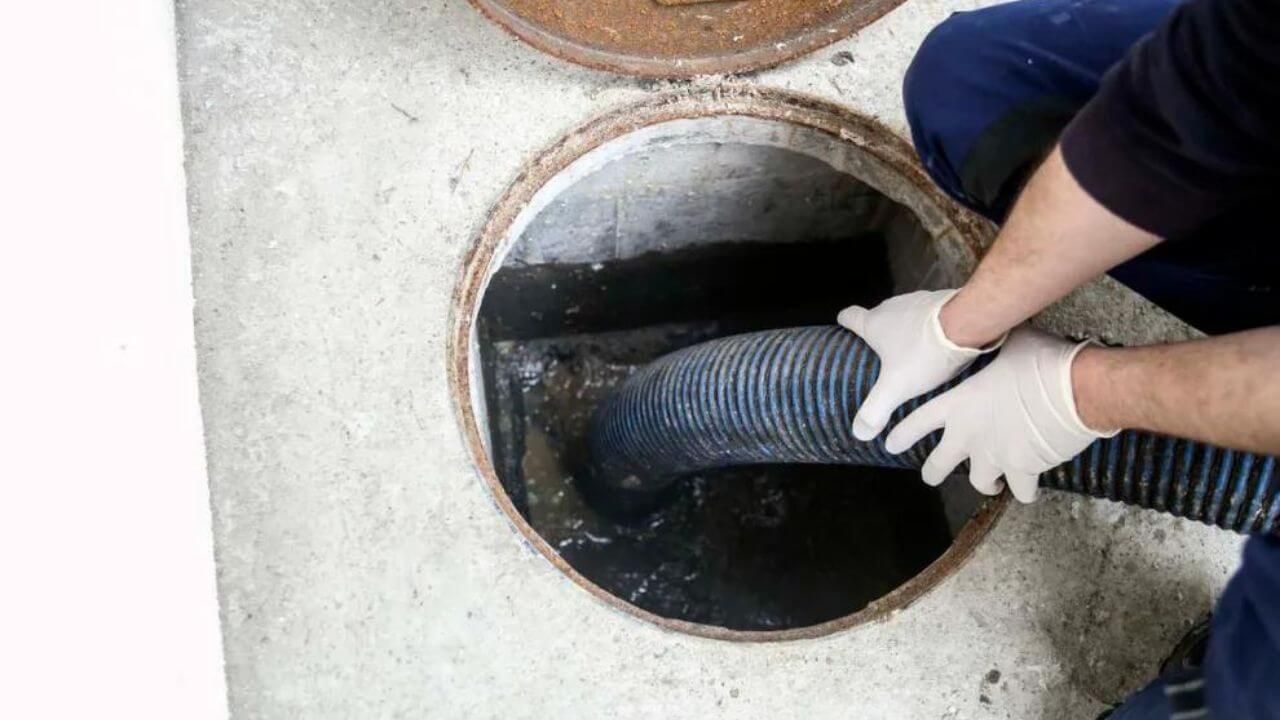 Man cleaning drain with hose.