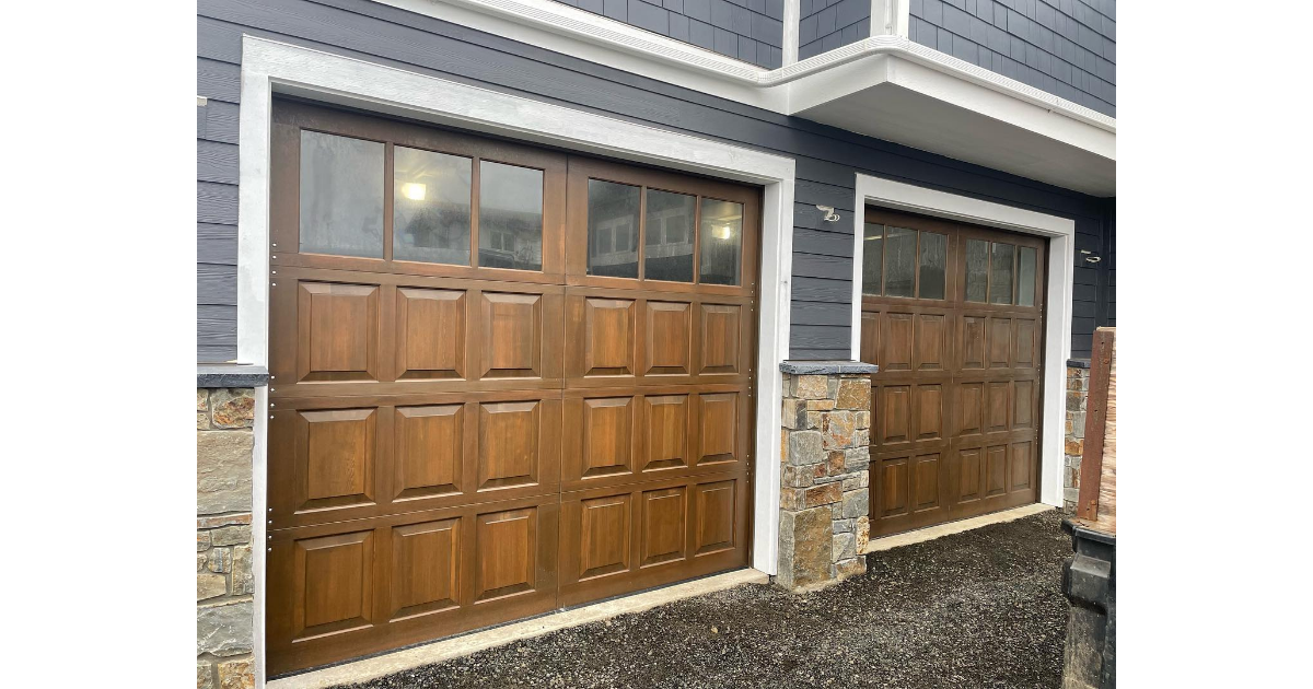 Two wood garage doors installed on residential home with stone accents