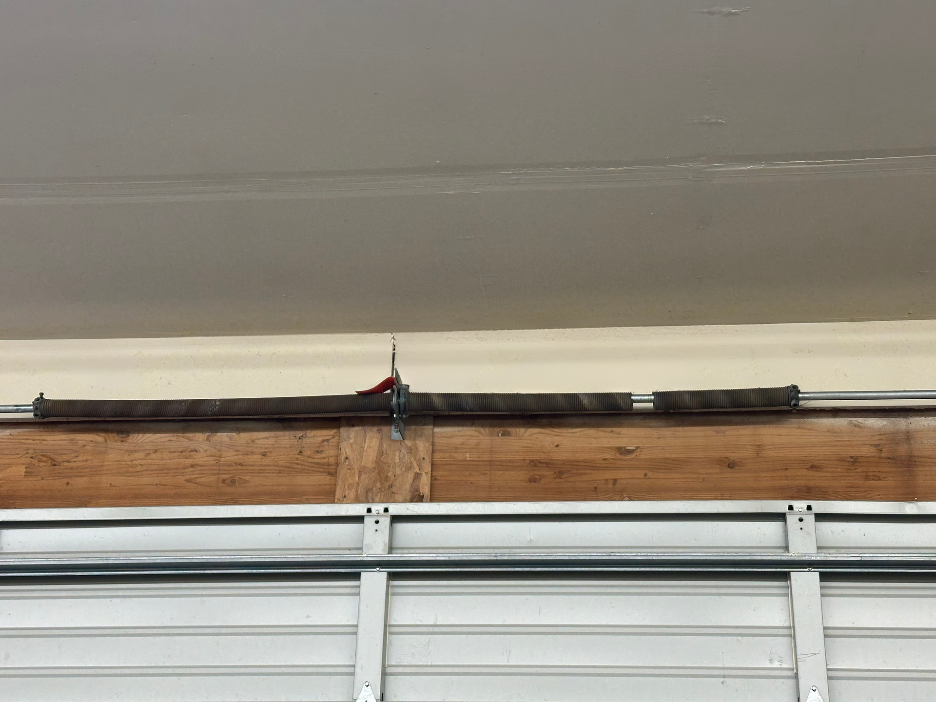 Close-up of broken garage door spring showing separation in coil on residential door
