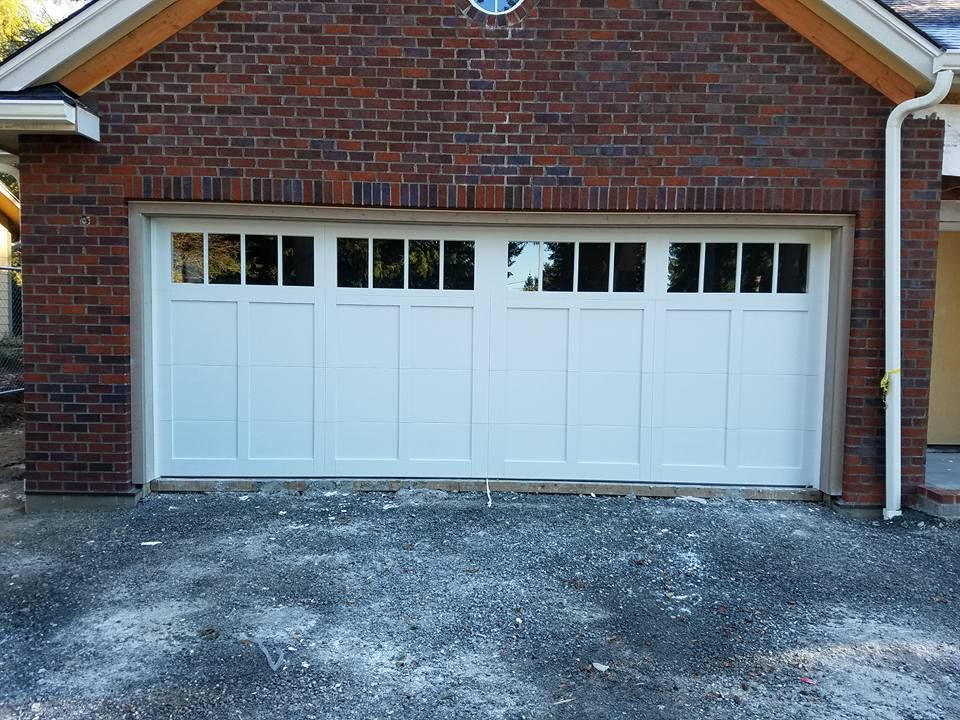 White garage door with window panels on brick home