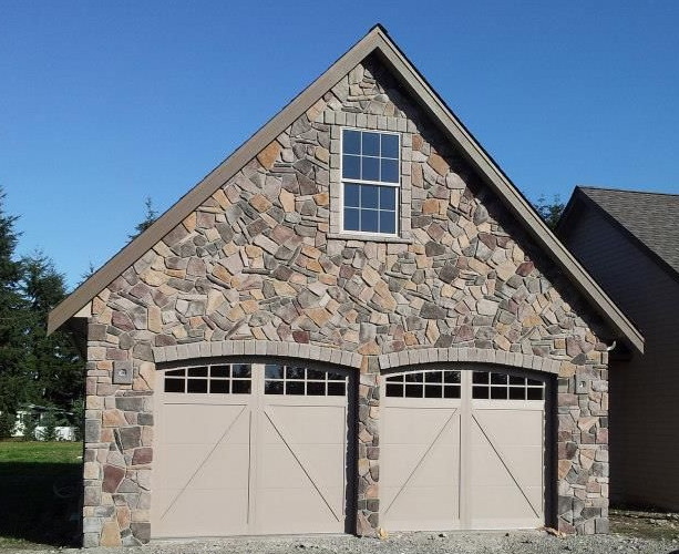 Two-car garage with carriage-style doors on a stone exterior home in Tumwater