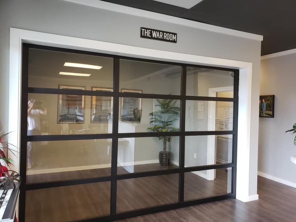 Modern indoor glass garage door installed in an office setting by Johnson & Johnson Overhead Doors INC