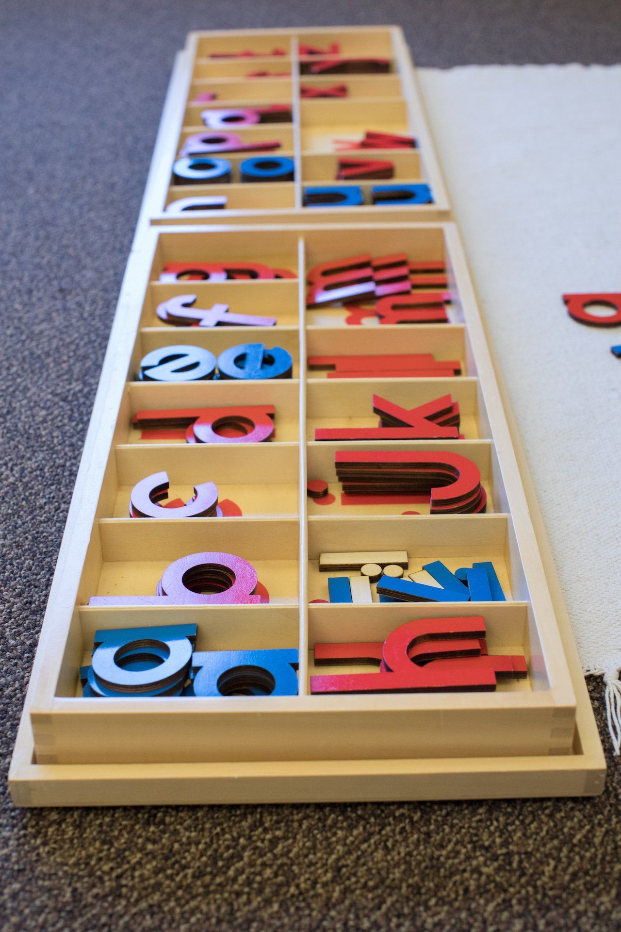 A wooden tray filled with montessori colorful wooden letters and numbers.