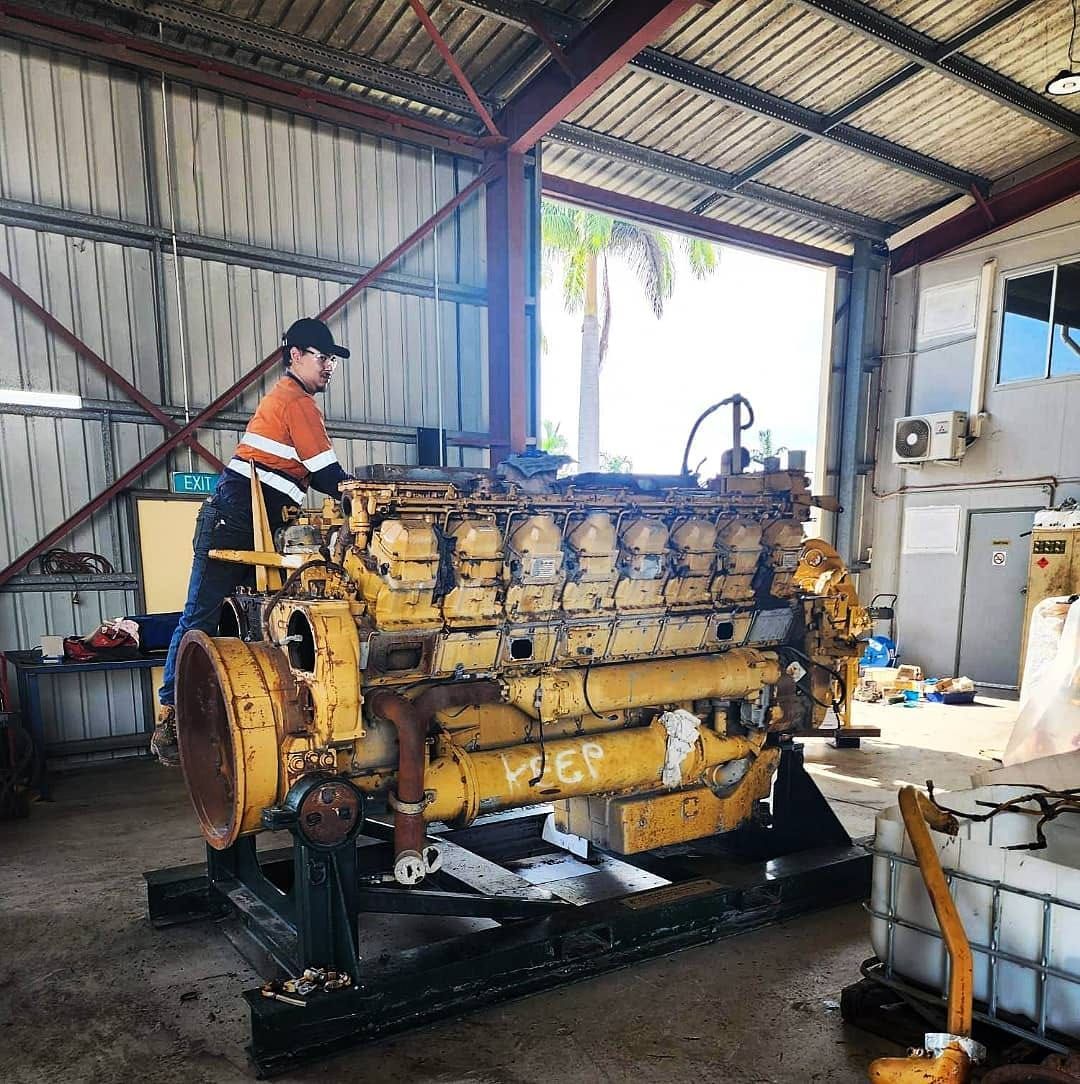 A man is working on a large yellow engine in a garage — KBX Mechanical In Paget, QLD