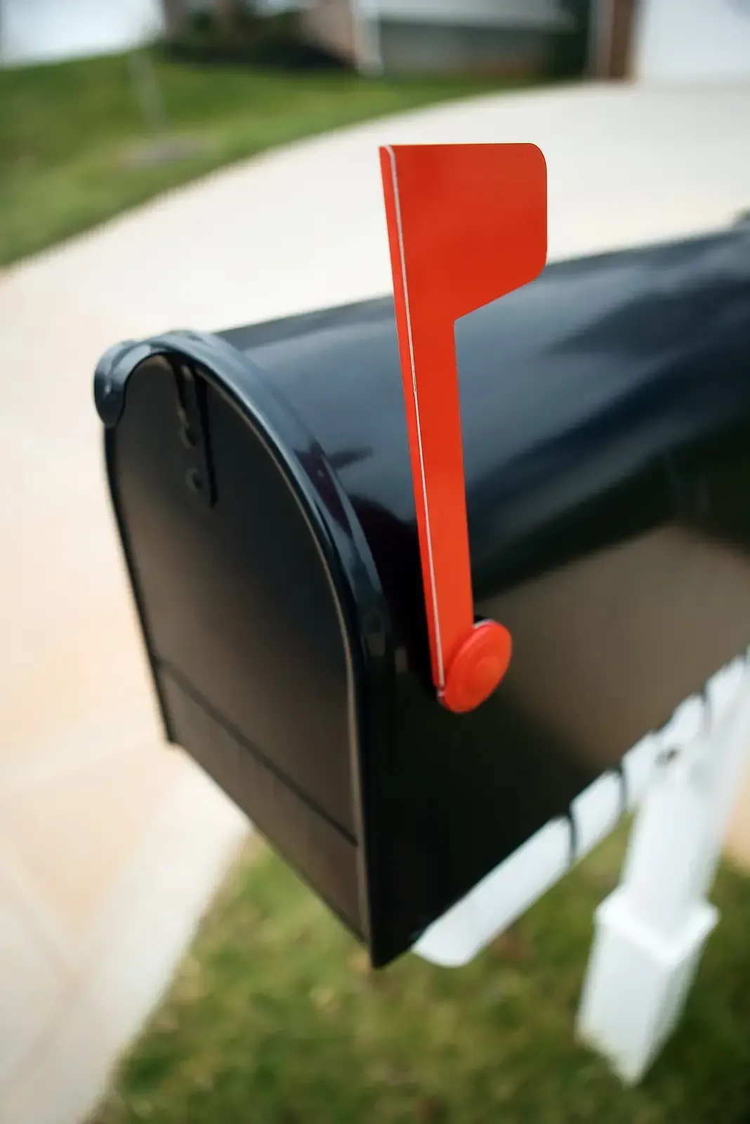 A close-up of a metal hinge and roller assembly on a white paneled garage door.