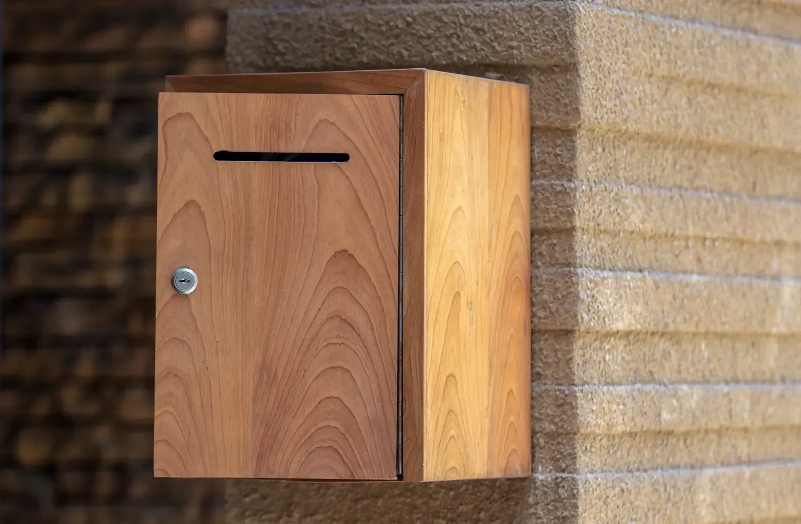 A hand adjusting the camera on a red and white LiftMaster garage door opener mounted on a wooden garage ceiling.