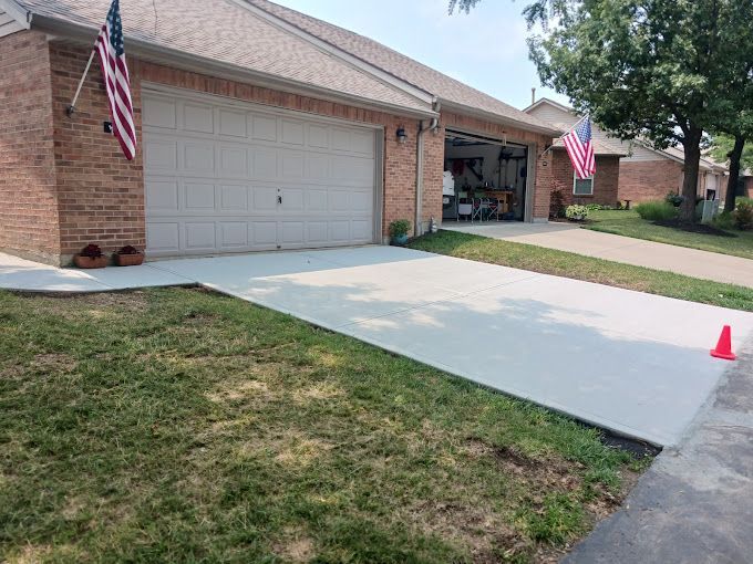 A brick house with a garage and a concrete driveway in front of it.
