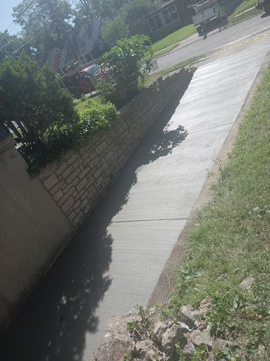 A sidewalk is being built next to a brick wall.