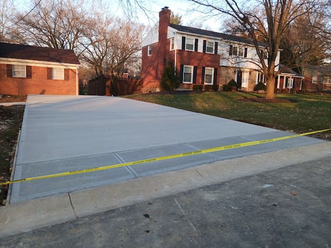 A brick house with a concrete driveway in front of it