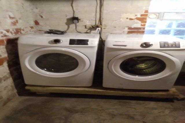 washer and dryer in basement next to window