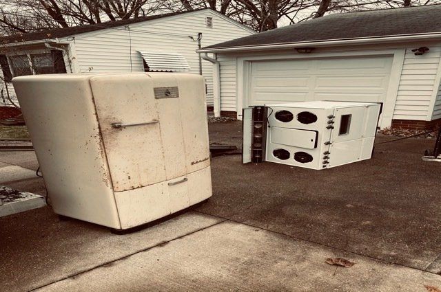 A Refrigerator and stove in a driveway in front of garage