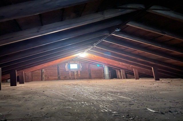 Empty attic with light turned on and a window