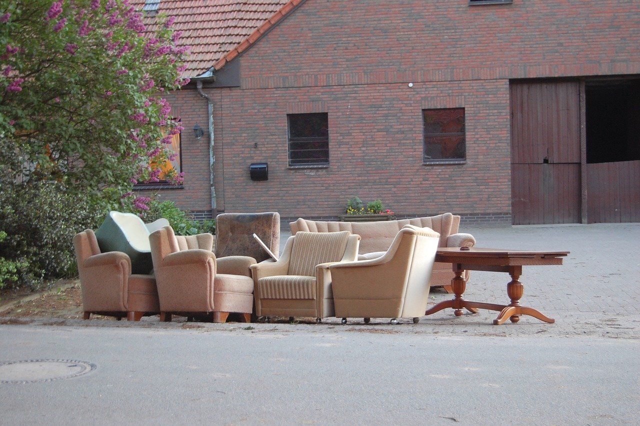Multiple furniture items (Including 5 chairs, a couch, and a table) left on a curbside to be hauled away