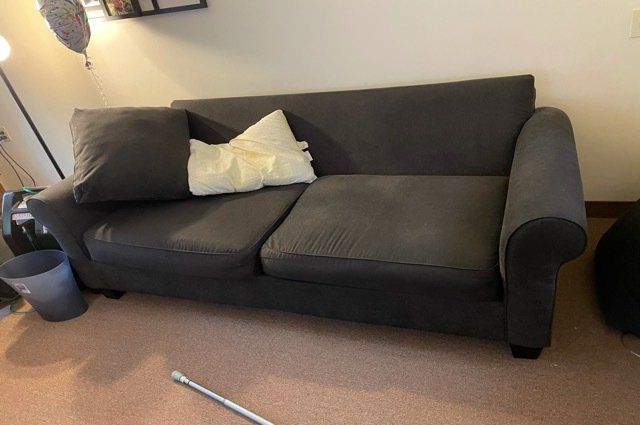 black couch with 2 pillows and a lamp beside it