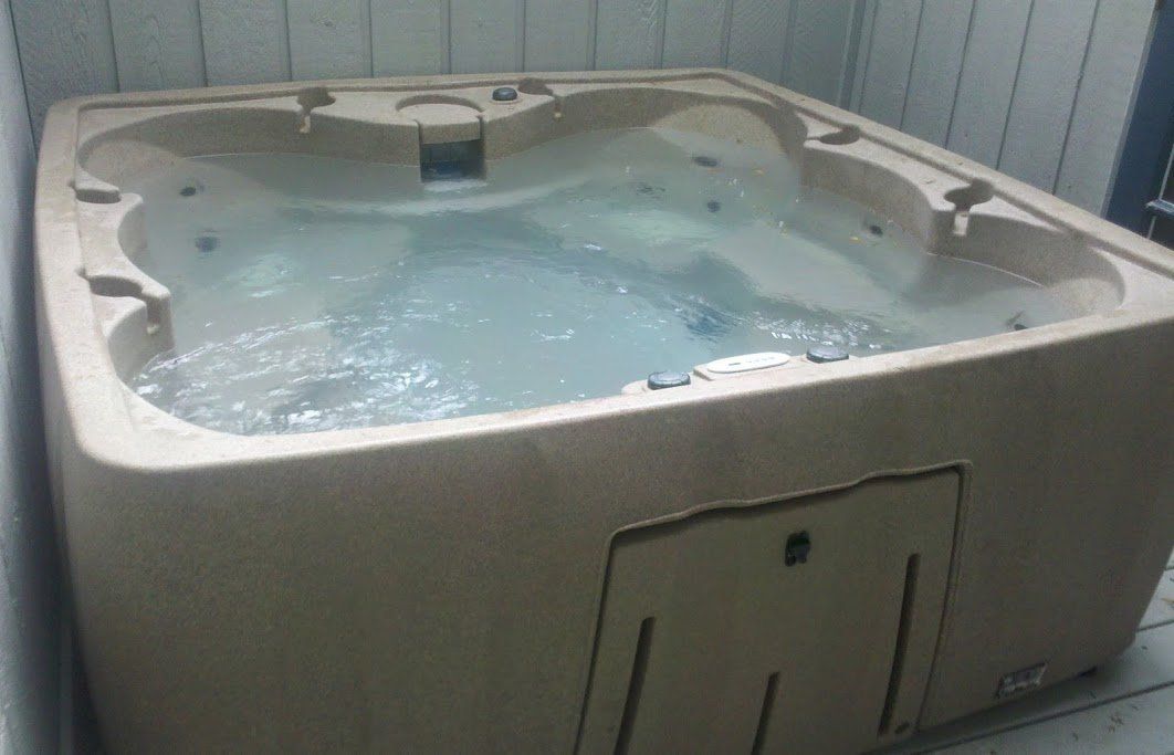 Old tan hot tub filled with water