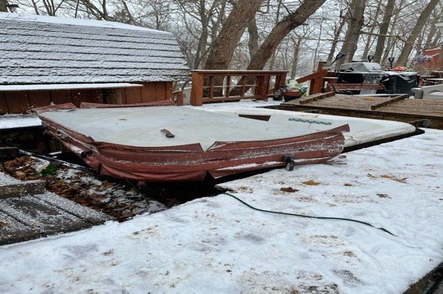 hot tub with red cover inside of wooden deck with snow on it