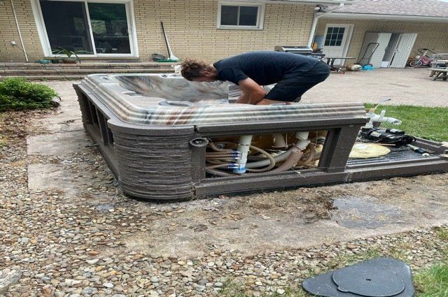 man inside of a hot tub that is missing panels in a back yard