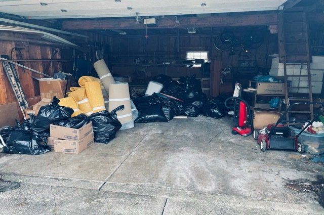 garage full of junk and black trash bags and rolled up carpet