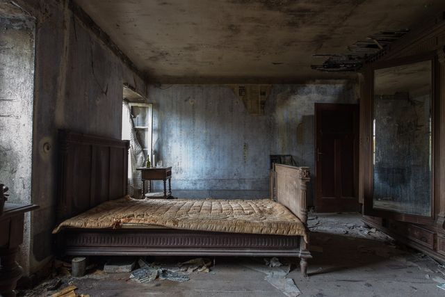 an old bed missing a mattress inside a distressed home