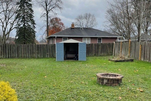 blue shed in back yard with doors open next to a fence and fire pit