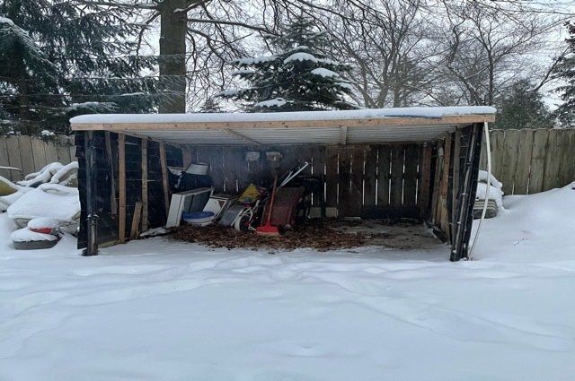 Shed with junk inside it and snow on ground around it