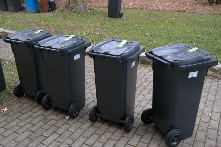 Row of four trash cans that are ready for pickup