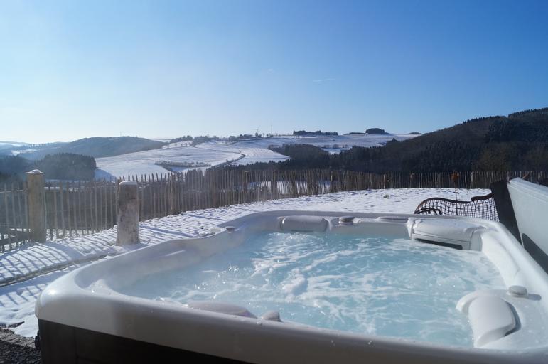 hot tub filled with water and running during the wintertime after a fresh coating of snow has fallen