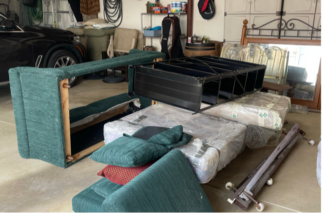 a green couch and a mattress and a shelf next to a car in a garage