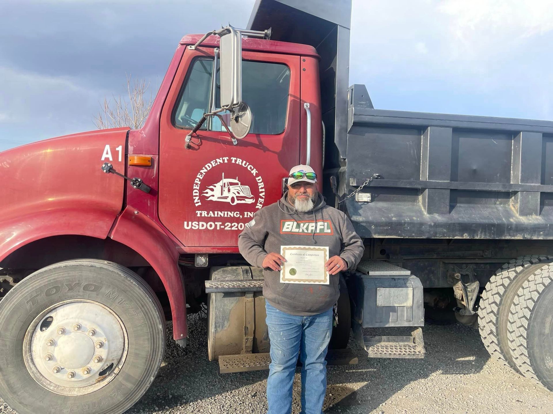 a man is standing in front of a dump truck holding a certificate .