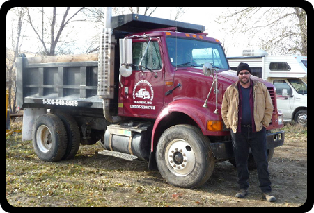 a man is standing in front of a red dump truck