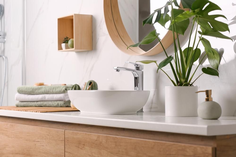 A Bathroom With A Sink , Mirror , Plant And Towels — Viison Kitchens & Joinery Forster In Taree, NSW
