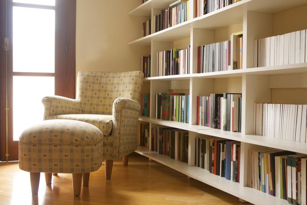 A Living Room With A Chair And Ottoman In Front Of A Bookshelf — Viison Kitchens & Joinery Forster In Wingham, NSW