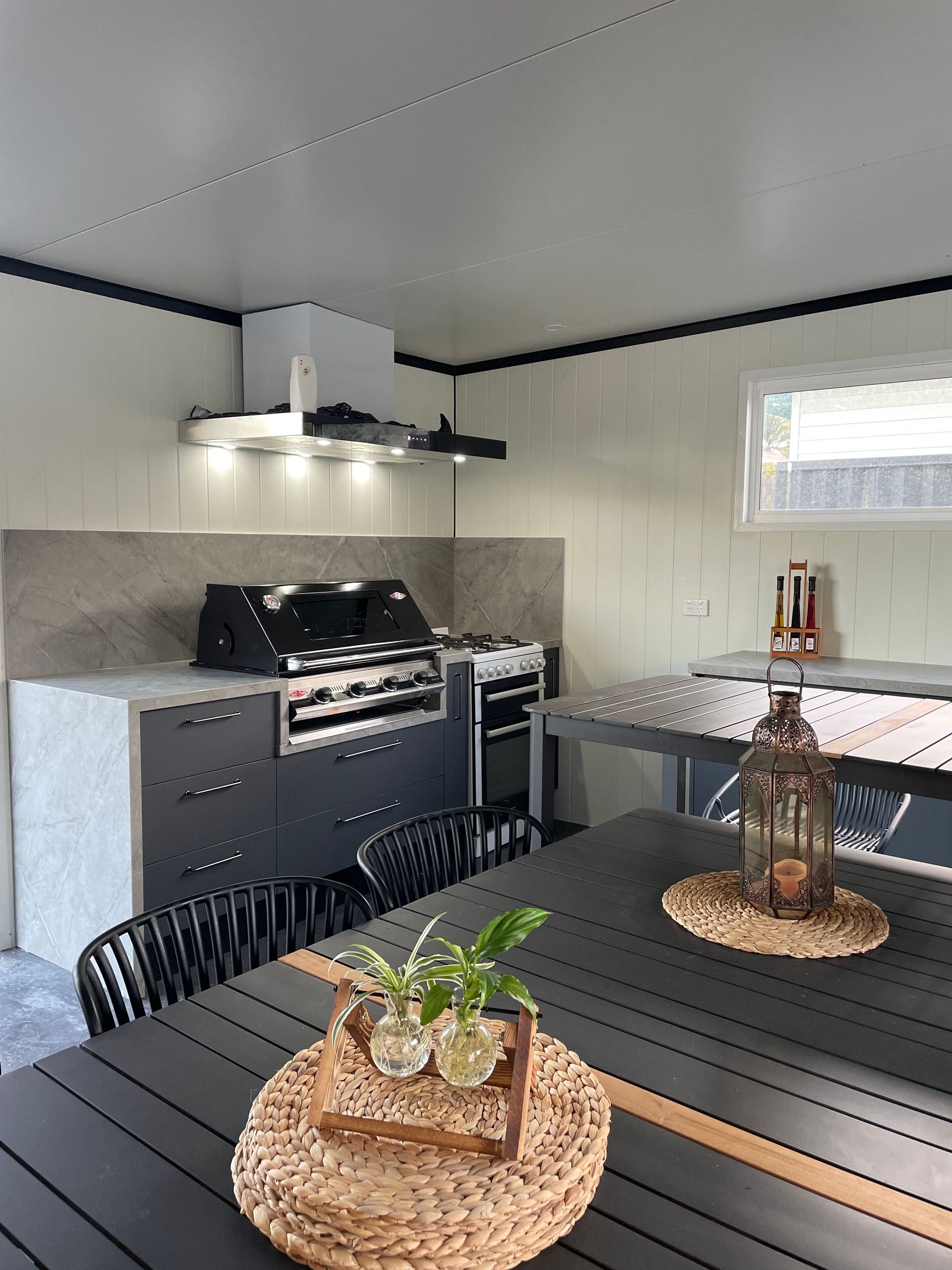 A Grey And White Outdoor Patio That Has An Outdoor Barbecue Area And Glass Ornaments On Tables — Viison Kitchens & Joinery Forster In Forster, NSW