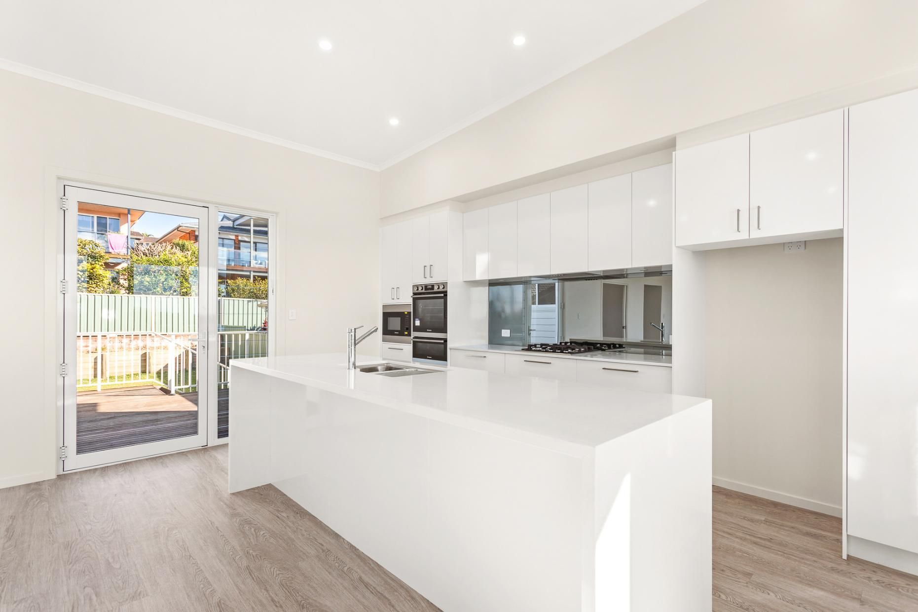 An Empty Kitchen With White Cabinets And A Large Island — Viison Kitchens & Joinery Forster In Kempsey, NSW