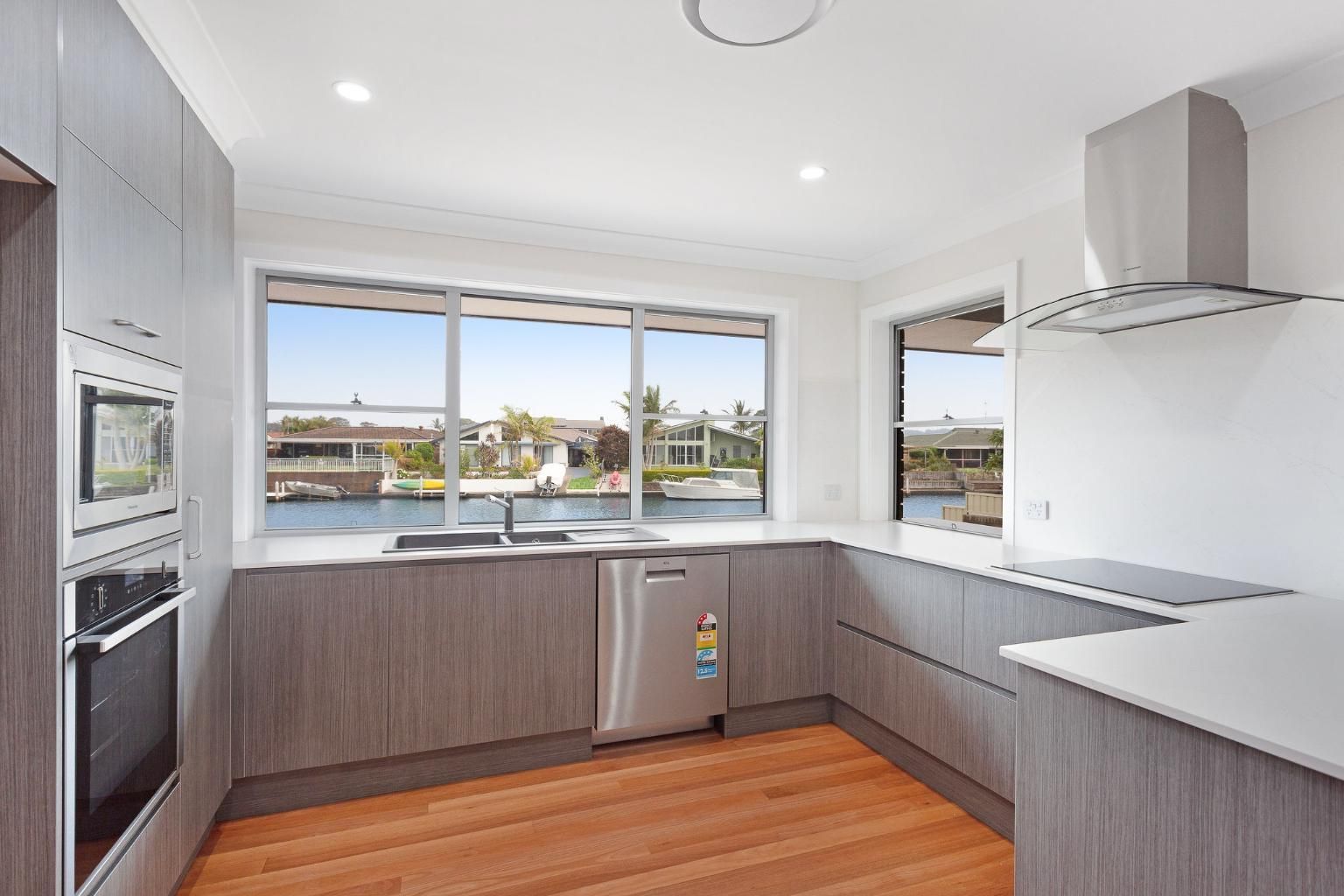 A Kitchen With Stainless Steel Appliances And Wooden Floors — Viison Kitchens & Joinery Forster In Forster, NSW