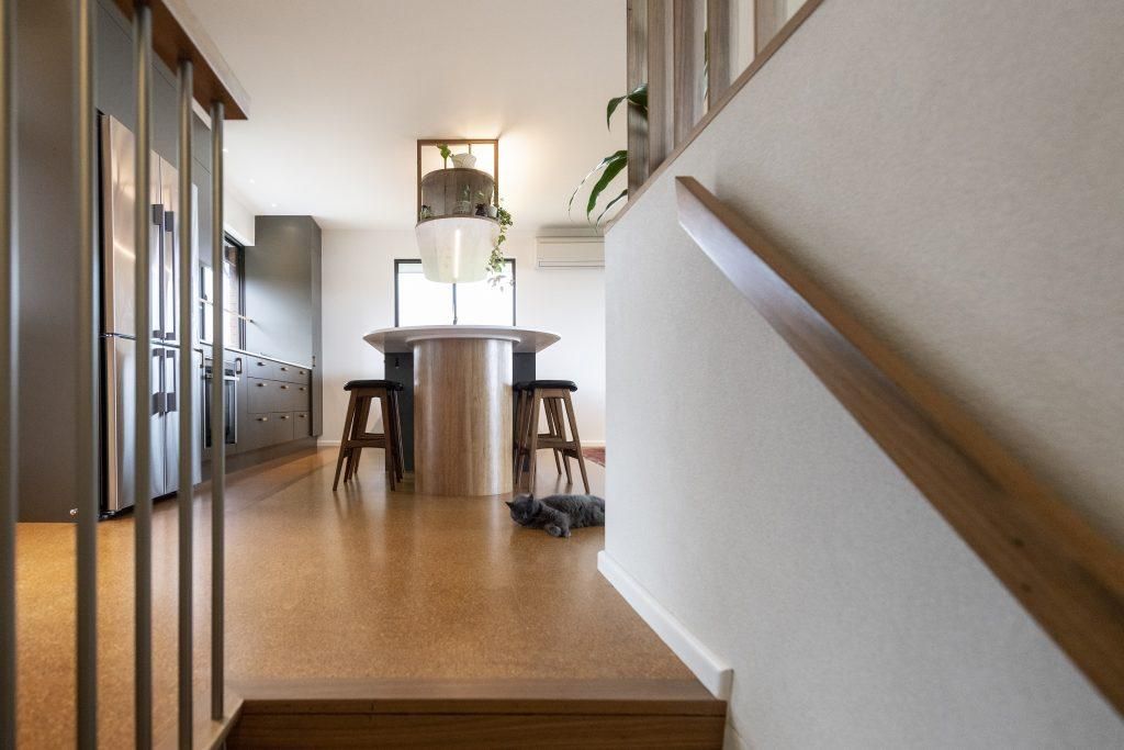 A Staircase Leading Up To A Kitchen With A Table And Stools — Viison Kitchens & Joinery Forster In Forster, NSW