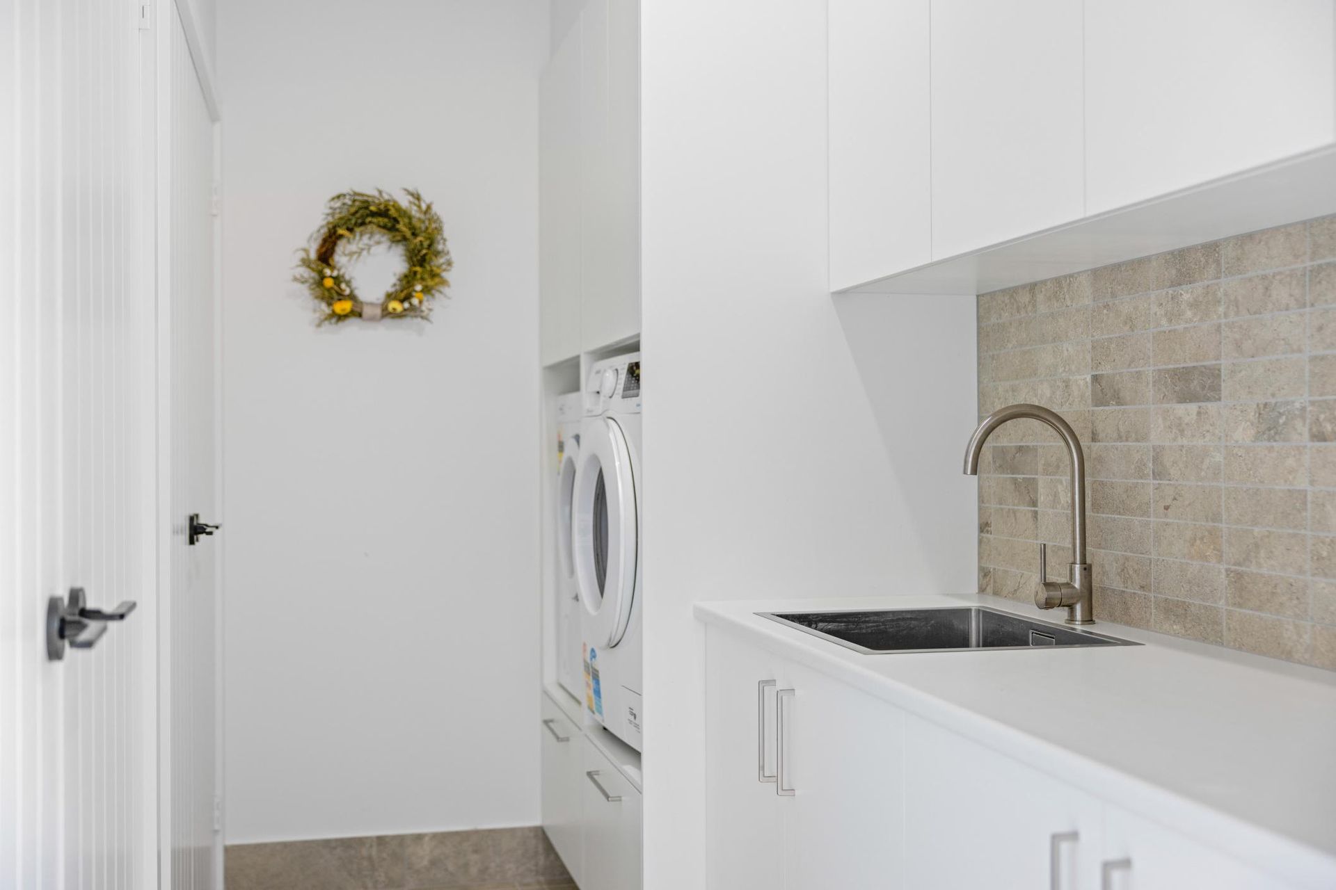 A Laundry Room With A Washer And Dryer , Sink , And Wreath On The Wall — Viison Kitchens & Joinery Forster In Forster, NSW