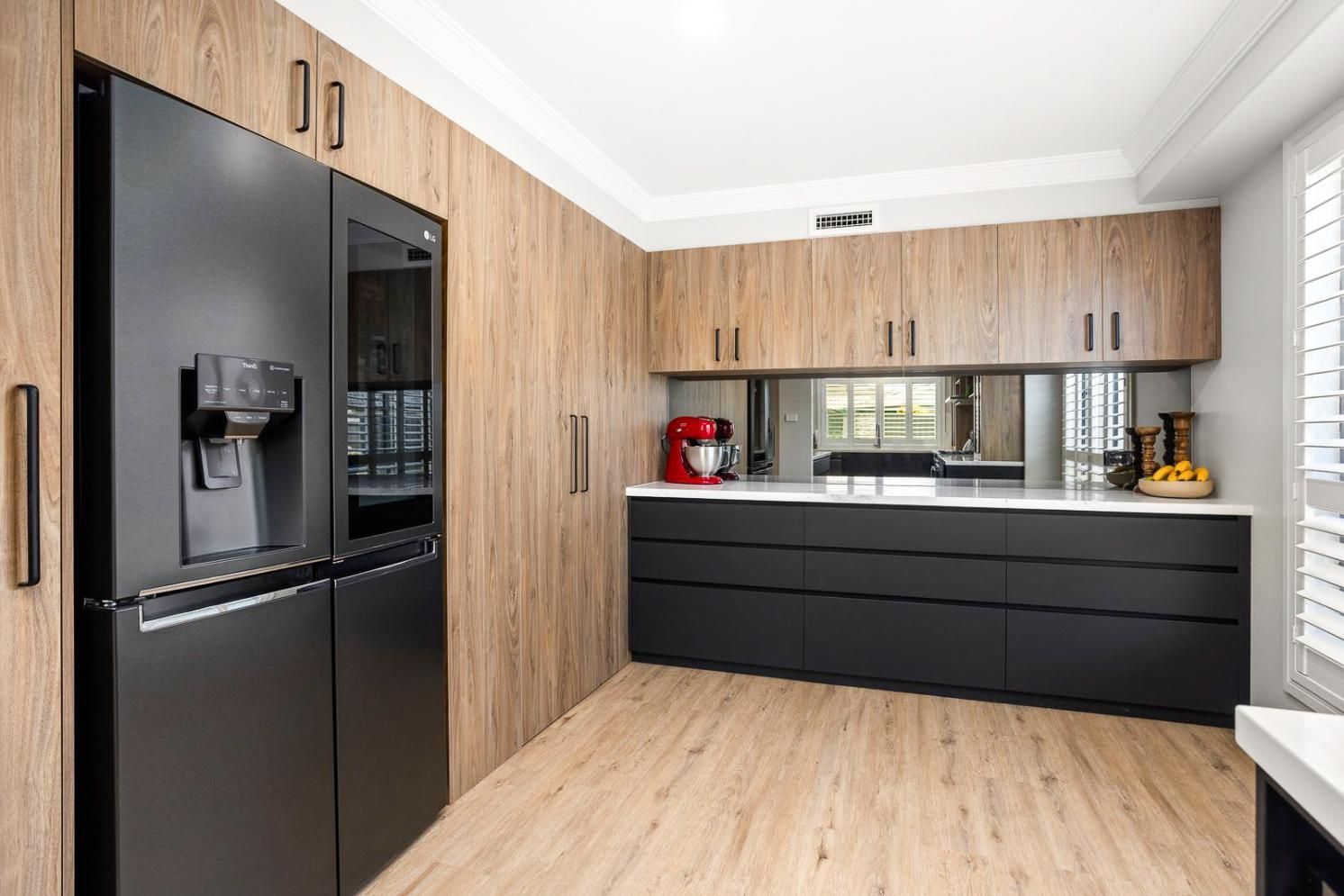 A Kitchen With Black Appliances And Wooden Cabinets — Viison Kitchens & Joinery Forster In Forster, NSW