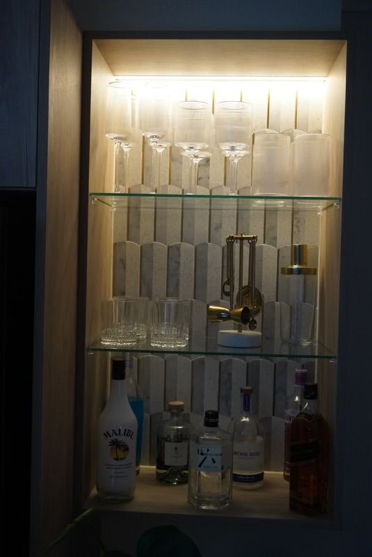 Lit-up liquor cabinet with various bottles and glassware on shelves. — Hallam & Sons in Beard, ACT