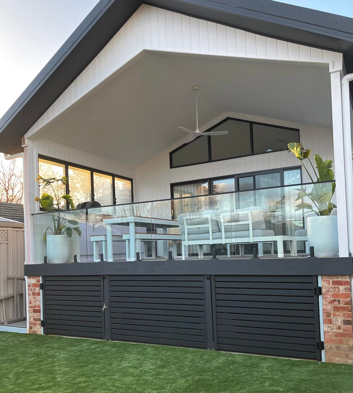 Yellow house with porch, white trim, and a green roof trim. Located on a green lawn. — Hallam & Sons in Beard, ACT