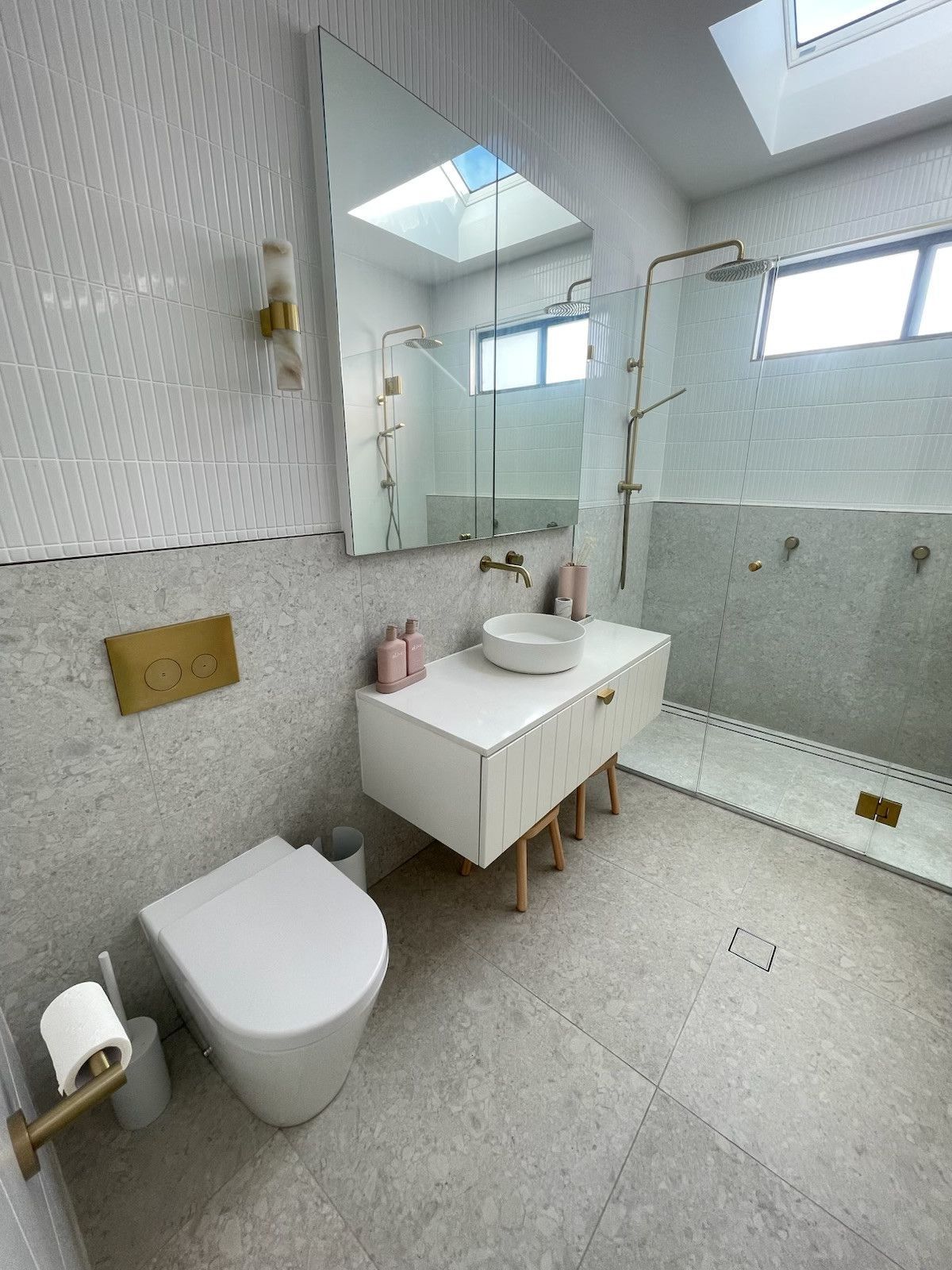 Modern bathroom with white and gray speckled tiles, white vanity, and gold fixtures. — Hallam & Sons in Beard, ACT