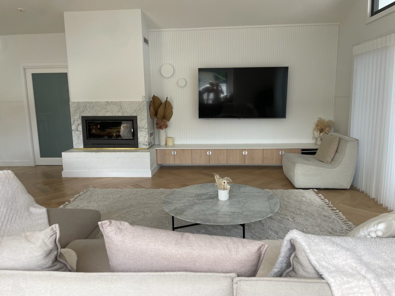 Living room with fireplace, TV, and coloured furniture, rug, and coffee table. — Hallam & Sons in Beard, ACT
