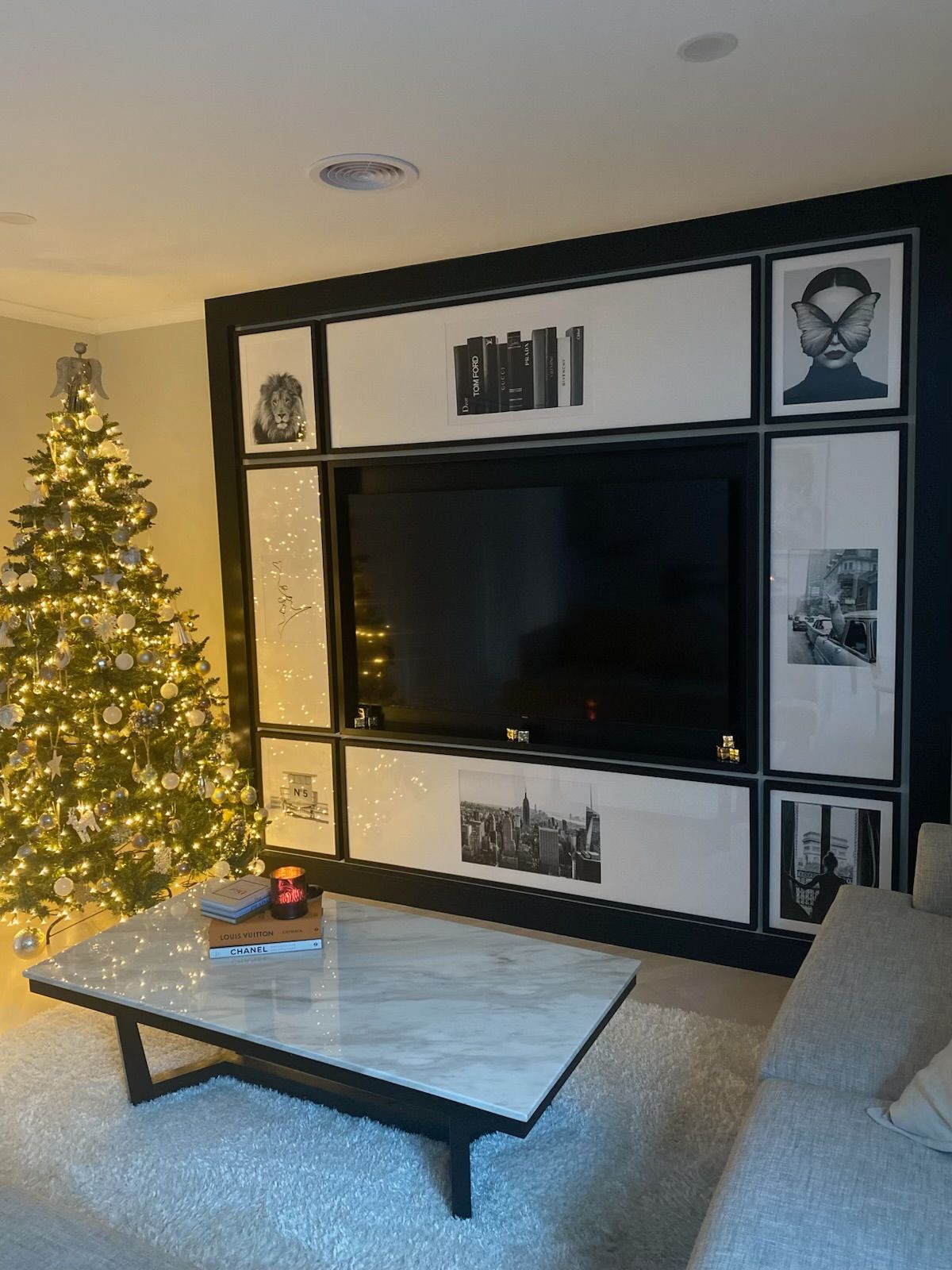 Christmas tree beside a TV wall unit with framed art and a marble-topped coffee table. — Hallam & Sons in Beard, ACT