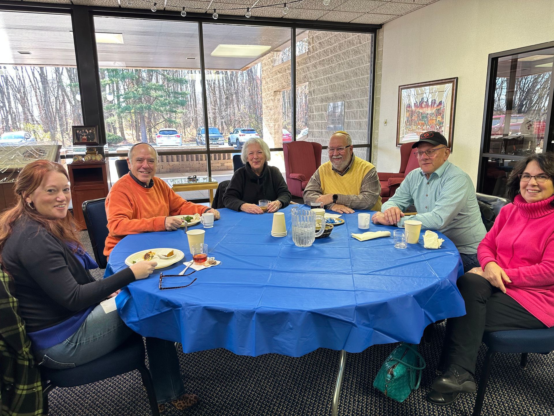 A group of people are sitting around a table with a blue tablecloth.