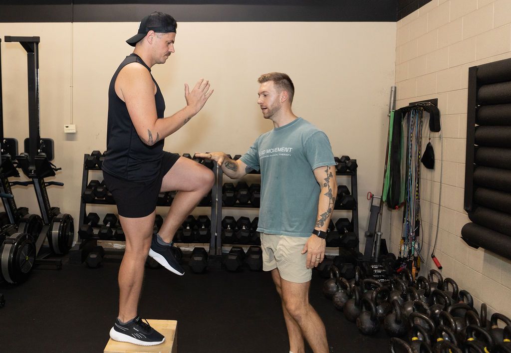 A woman is sitting on an exercise ball with a green resistance band.